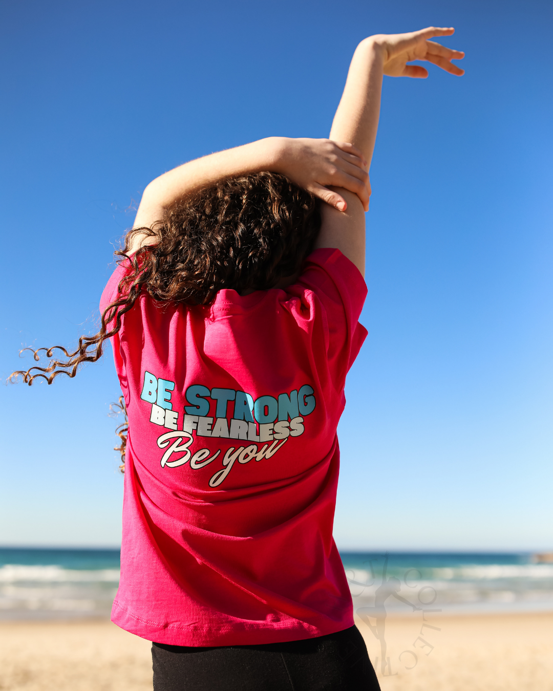 Person wearing a red t-shirt with motivational text on a beach