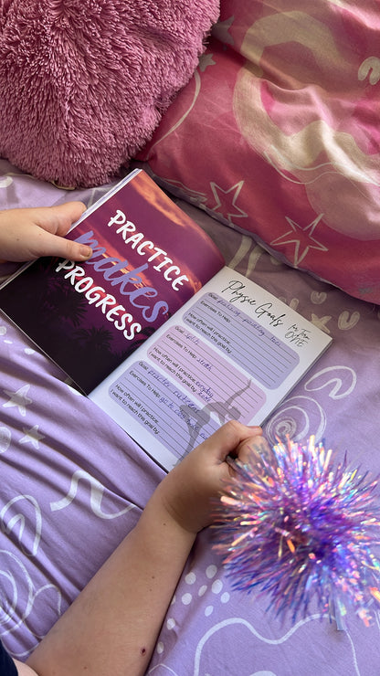 Person holding a book titled 'Practice Makes Progress' on a bed with pink pillows and a purple blanket.